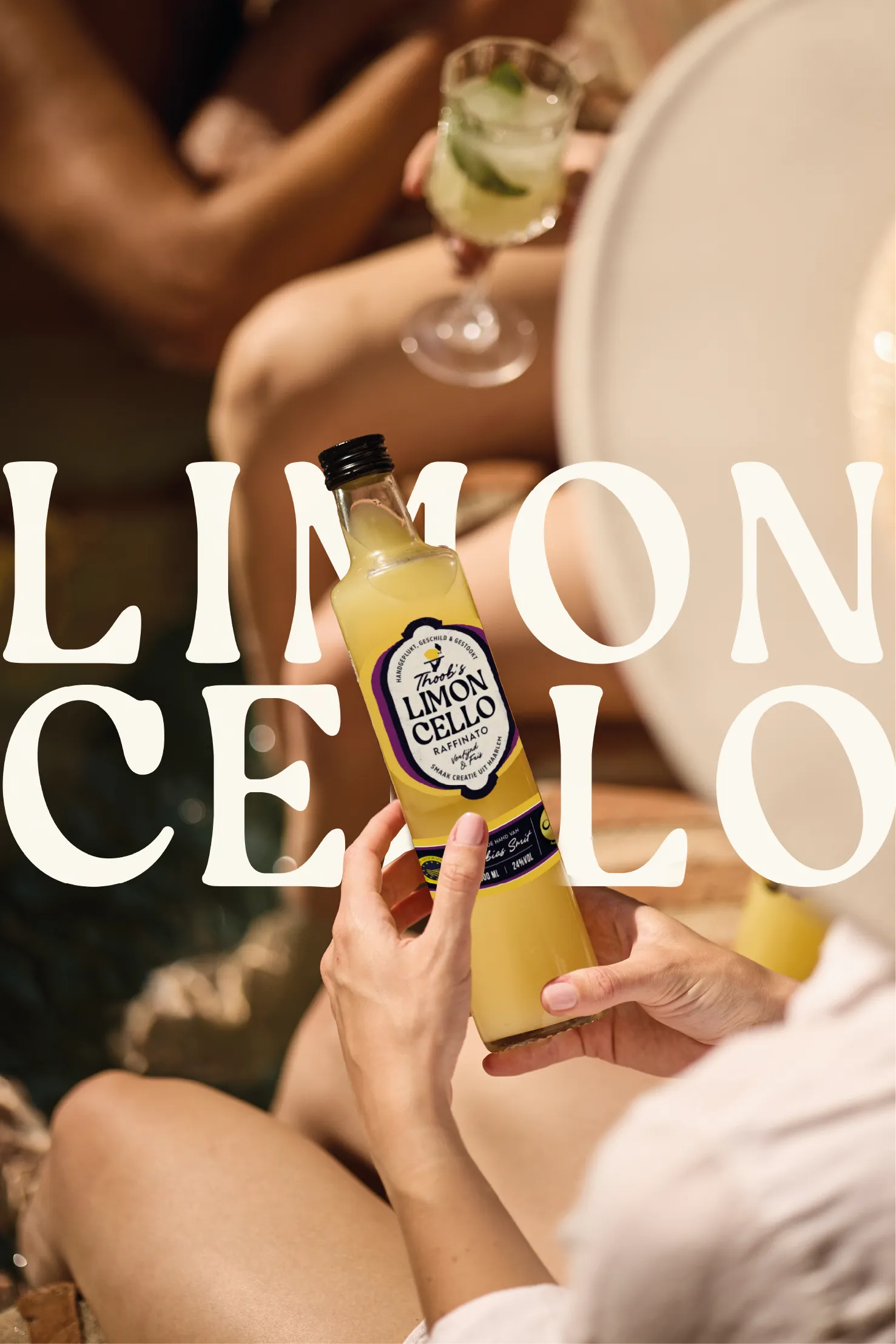 Limoncello fles met geel label en glas limoncellolikeur met citroen en ijsblokjes op wit bord